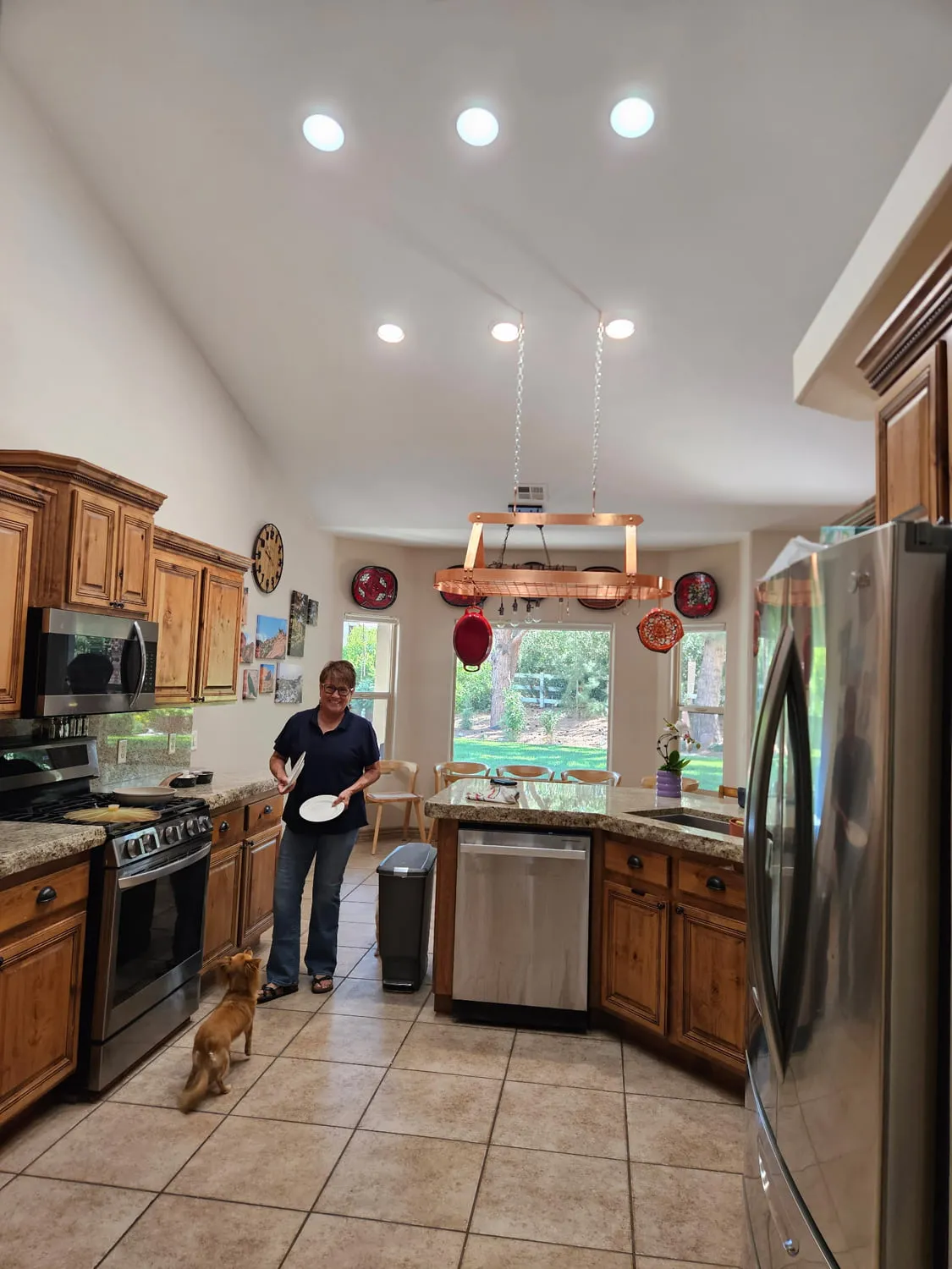 The same kitchen with the ceiling soffit removed, new recessed lighting installed in the open vaulted ceiling, and a copper pot rack hung from chains